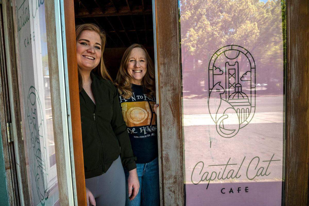 Capital Cat Cafe owners Emalee Ousley, left, and her mother Laura Ousley, right, peek out of the front door of their planned midtown business during construction in 2022.