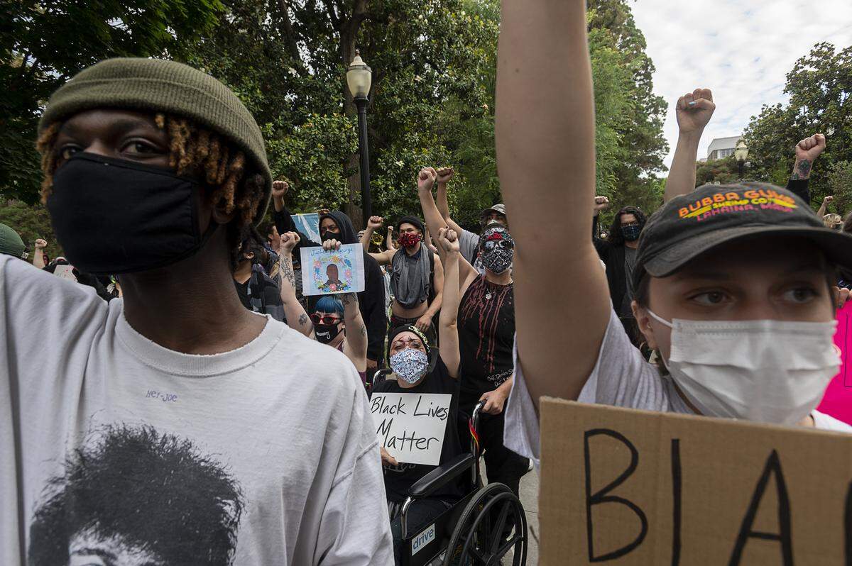 Demonstrators raise their arms in support during a protest over the death of George Floyd at the State Capitol on Sunday, May 31, 2020 in Sacramento during the coronavirus pandemic. George Floyd died in Minneapolis May 25 after being restrained by police.