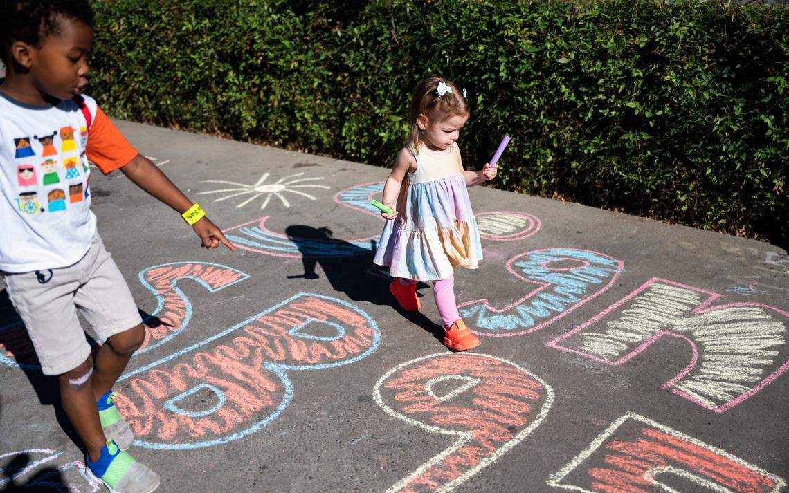 MacKenzie Jenkins, left, and Araceli Brennand color with chalk Friday before a march to urge Gov. Gavin Newsom to sign Senate Bill 951, which would expand access to California’s paid family leave program by increasing the amount paid to lower-wage employees who use the system. During the march, word arrived that the governor had signed the bill.