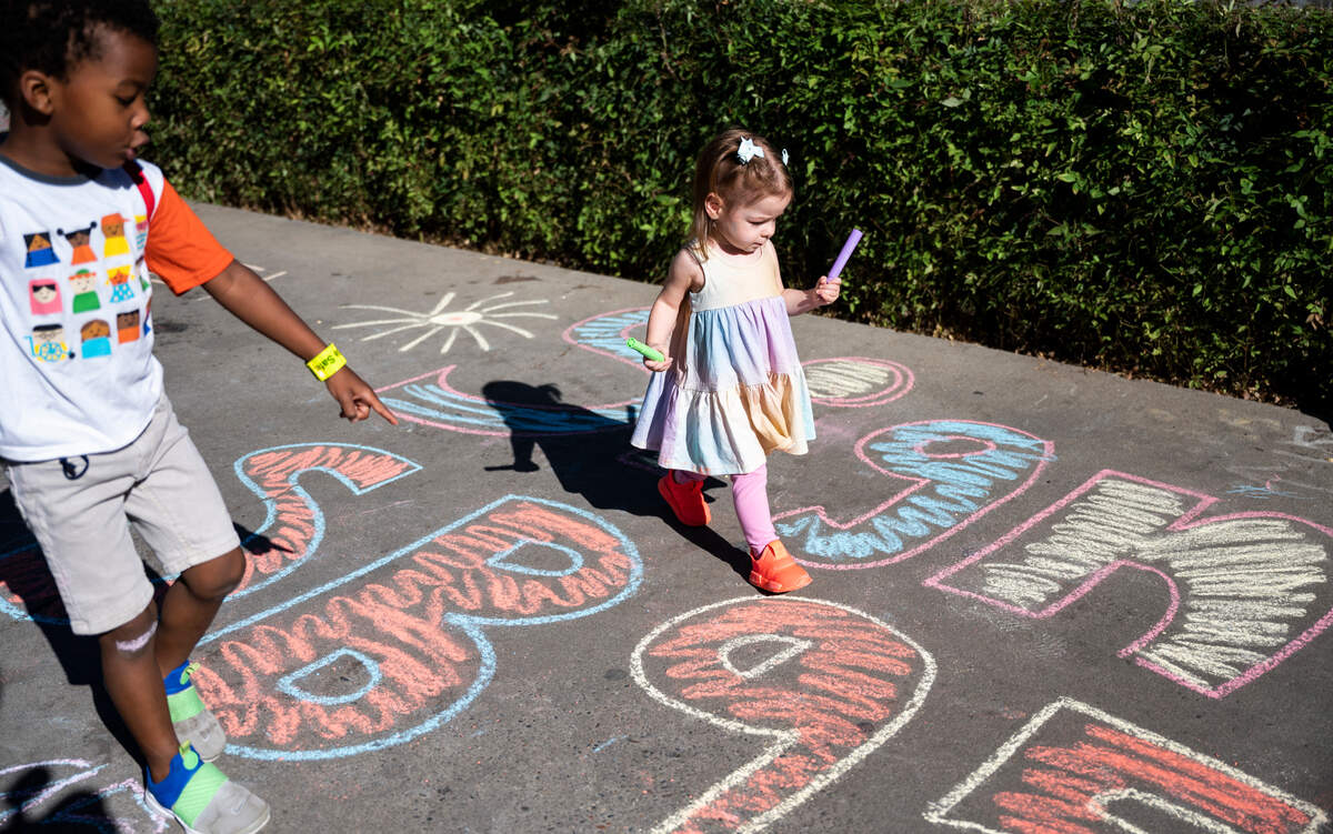 MacKenzie Jenkins, left, and Araceli Brennand color with chalk Friday before a march to urge Gov. Gavin Newsom to sign Senate Bill 951, which would expand access to California’s paid family leave program by increasing the amount paid to lower-wage employees who use the system. During the march, word arrived that the governor had signed the bill.