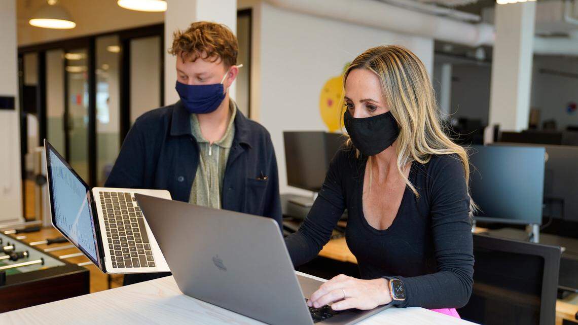 Kelly Soderlund, right, works with a colleague at the TripActions office in San Francisco, Friday, Aug. 27, 2021. Switching to a hybrid work model is ideal for people like Soderlund, a mother of two young children who works in offices in San Francisco and Palo Alto, California, for TripActions, which has about 1,200 employees worldwide. (AP Photo/Eric Risberg)