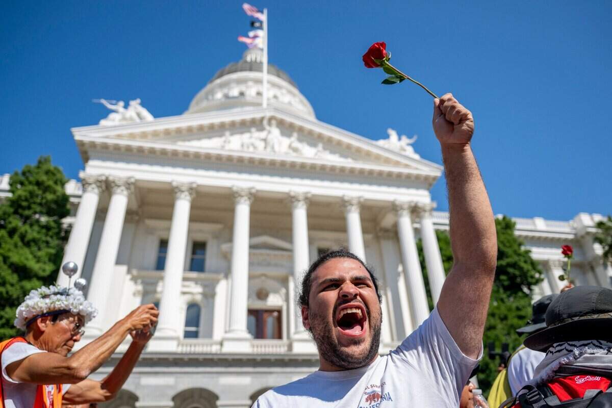 Diego Roman Hernandez holds up a rose Monday in celebration showing that he made the three-day march for immigrant rights from Vacaville to the state Capitol.
