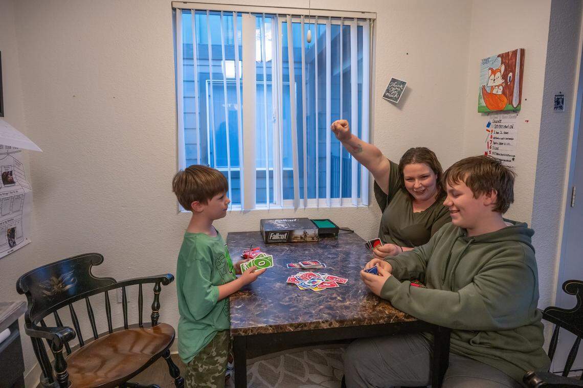 Katie Horton gestures in celebration while playing a card game in her apartment in Lincoln with her sons, Waylon, 6, and Chance, 11, on Wednesday. She said she hopes someday to save enough to send them to college.