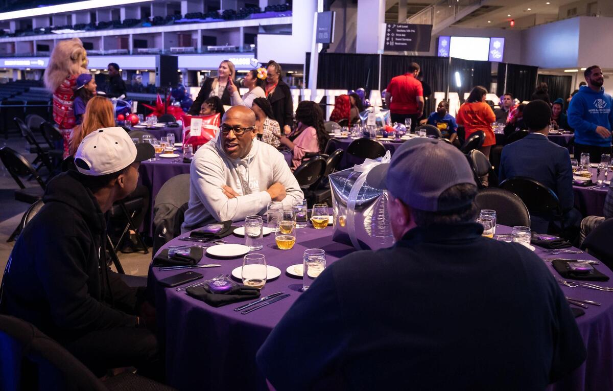 Sacramento Kings head coach Mike Brown socializes at a table while his players serve community members food during the “Eat Like a King” event Wednesday. The event is part of the organization’s 21st Annual Season of Doing Good, presented by Raley’s.