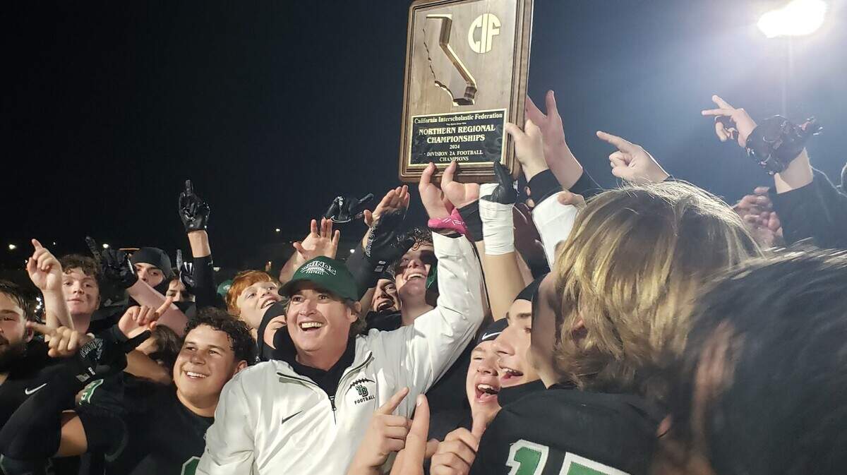 Twelve Bridges head coach Chris Bean helps his players hoist the CIF NorCal Division 2-A championship plaque after defeating Wilcox of Santa Clara, 28-27, on Saturday and advancing to the first state title game in school history.