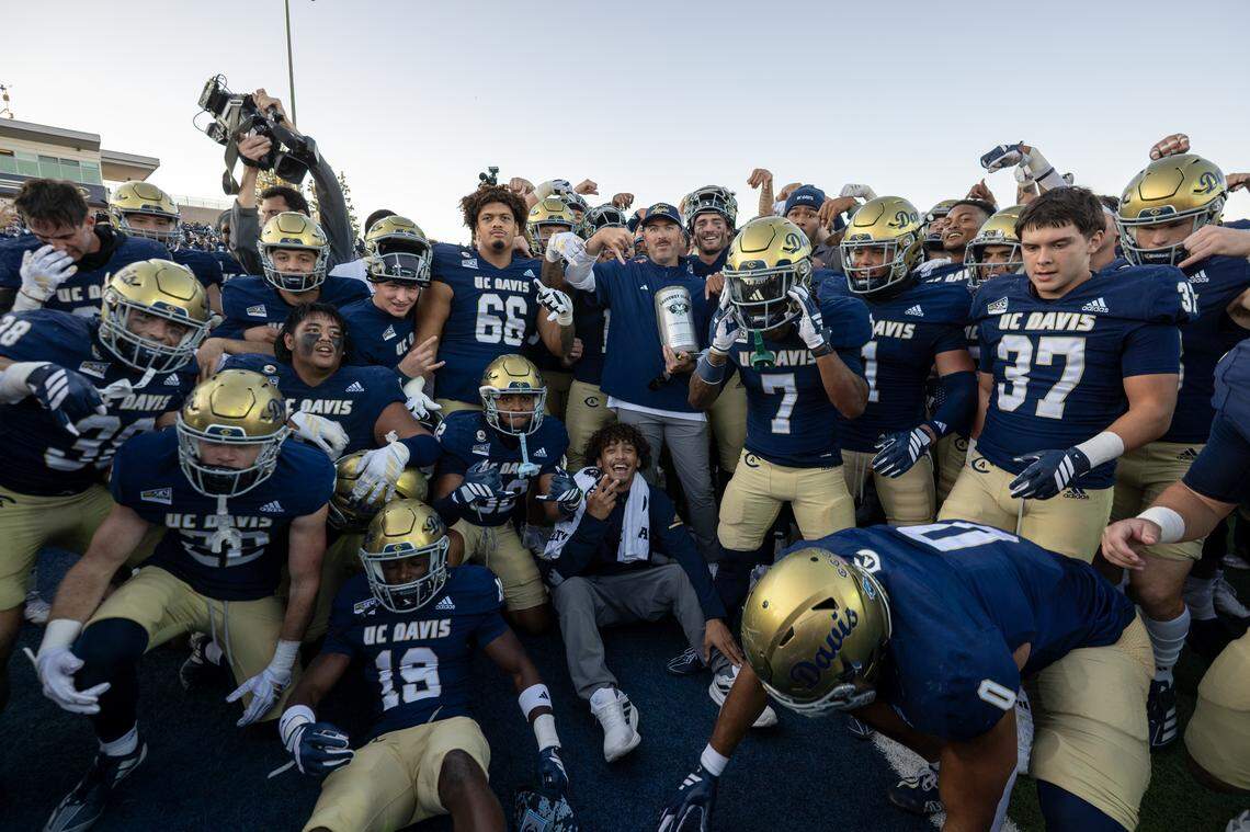 UC Davis Aggies head coach Tim Plough holds the Causeway Carriage trophy with the Aggies football team by his side following the 31-27 victory over the Sacramento State Hornets in the Causeway Classic on Saturday, Nov. 22, 2025 in Davis.