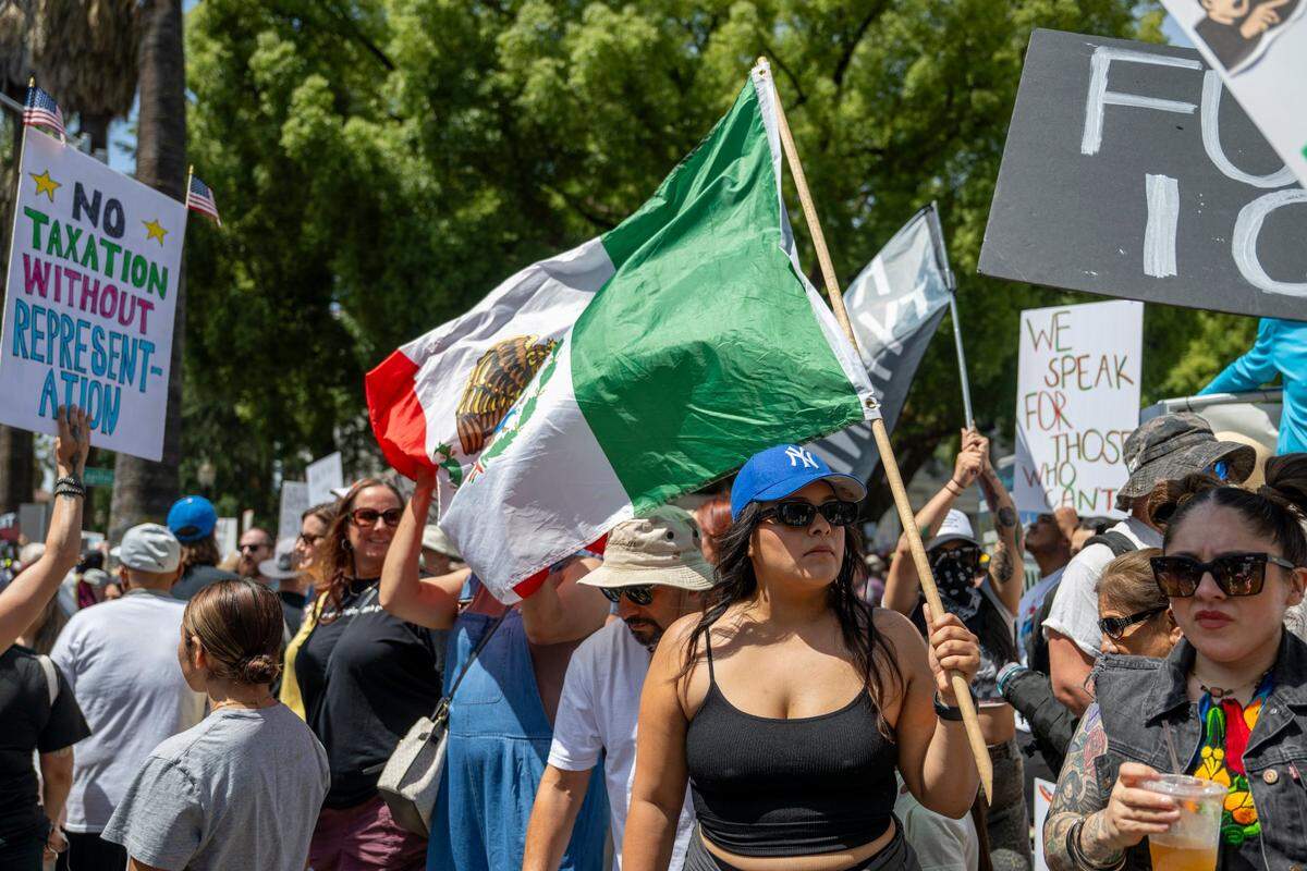 A demonstrator holds a Mexican flag near the state Capitol during the “No Kings” protest against the Trump administration in downtown Sacramento on Saturday.