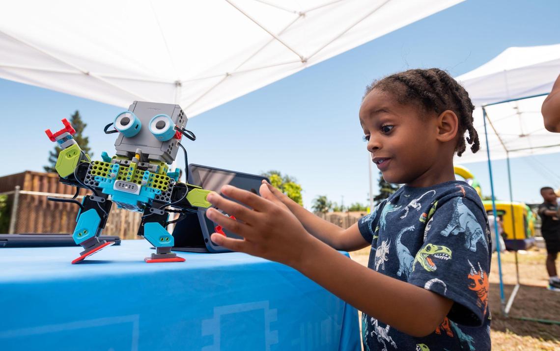 Caysen Salahuddin, 5, of Sacramento, controls the dancing of one of the Jimu MeeBots, an educational coding and modeling robotic kit, at a Square Root Academy table during the H@ck the Park outdoor festival Saturday. “That’s a breakdance,” he exclaimed.