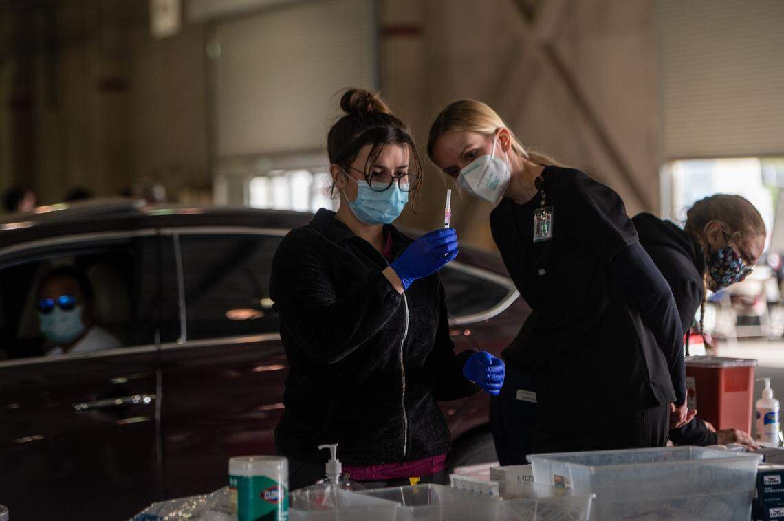 Jenny Ravailov, a medic with the California National Guard, prepares a COVID-19 Moderna vaccine alongside Nurse Katherine Ambrose, right, of the Sacramento Medical Reserve Corps at a drive up Sacramento County Public Health clinic at Cal Expo on Thursday, Jan. 21, 2021.