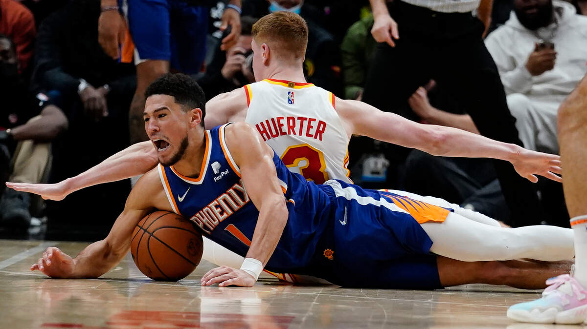 Phoenix Suns guard Devin Booker (1) and Atlanta Hawks guard Kevin Huerter (3) dive for the ball during the second half of an NBA basketball game Thursday, Feb. 3, 2022, in Atlanta. (AP Photo/John Bazemore)