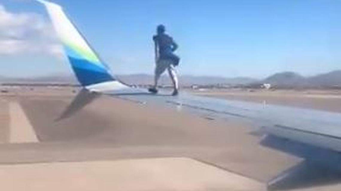 An intruder at the Las Vegas, Nevada, airport climbs onto the wing of an Alaska Airlines jet, then falls off as officers approach, a video shows.