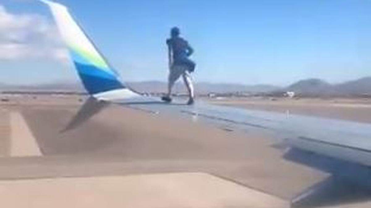 An intruder at the Las Vegas, Nevada, airport climbs onto the wing of an Alaska Airlines jet, then falls off as officers approach, a video shows.