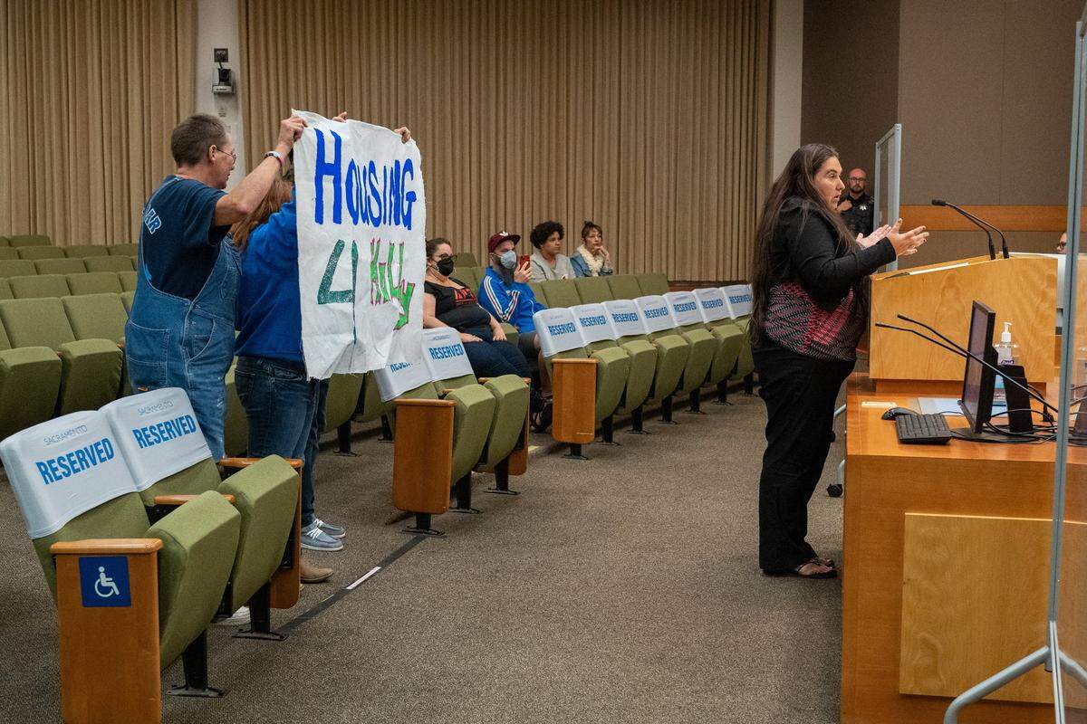 Crystal Sanchez, president of the Sacramento Homeless Union, speaks during the public comment matters not on the agenda at the end of Sacramento City Council meeting questioning why Holly Porter is not housed as advocates from Camp Resolution hold up a sign in Holly’s behalf on Tuesday.