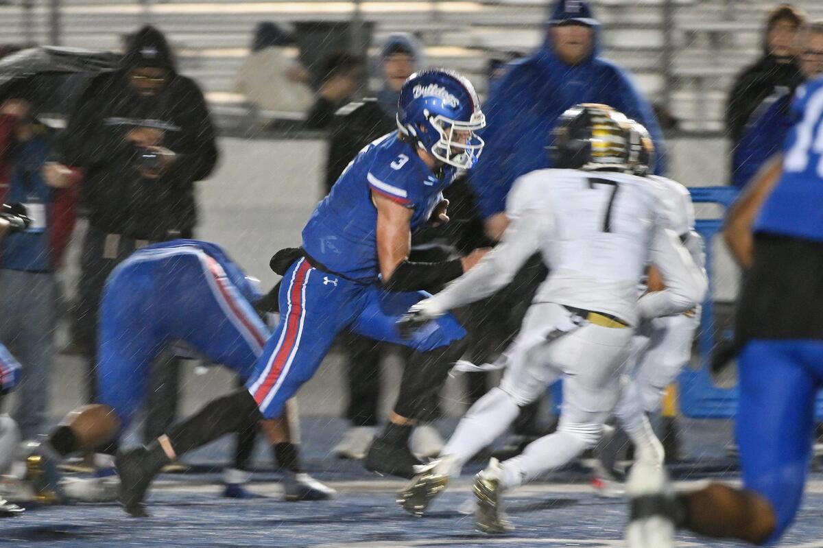 Folsom Bulldogs quarterback Ryder Lyons (3) runs the ball for 16 yards as rain pours down in the second half of a CIF Sac-Joaquin Division I semifinal game against the Inderkum Tigers on Friday.