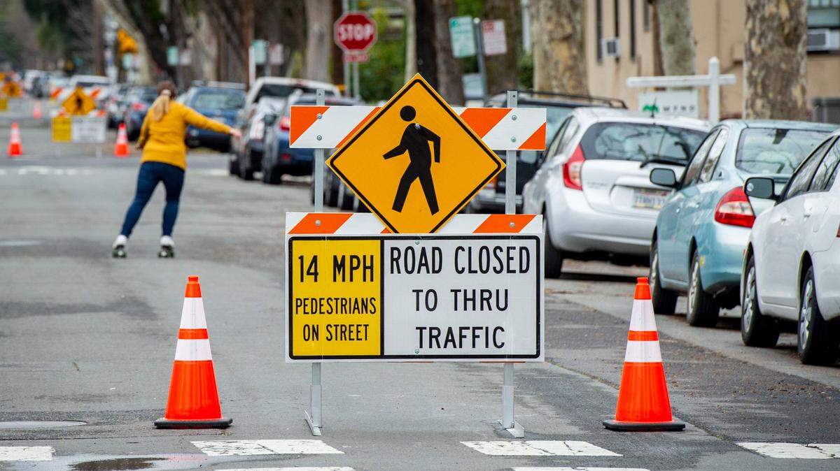 A woman roller skates down 26th Street in midtown Sacramento on Monday, Feb. 15, 2021, between new street signs put up by the city as part of a “slow and active streets” initiative to encourage more people to get out of their cars and utilize the road space. The latest of several street closures covers 12 blocks of 26 between J and V streets.