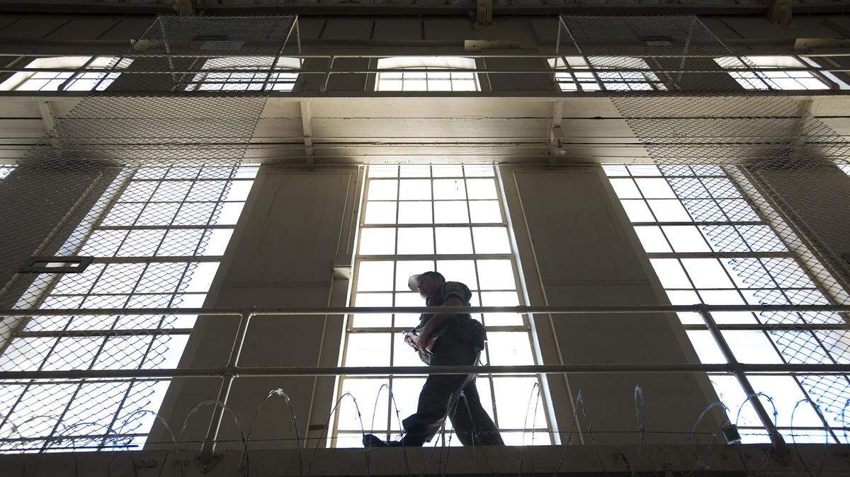 A prison guard carries his weapon while he walks along a catwalk inside East Block at San Quentin State Prison on Tuesday, December. 29, 2015, in San Quentin, Calif.