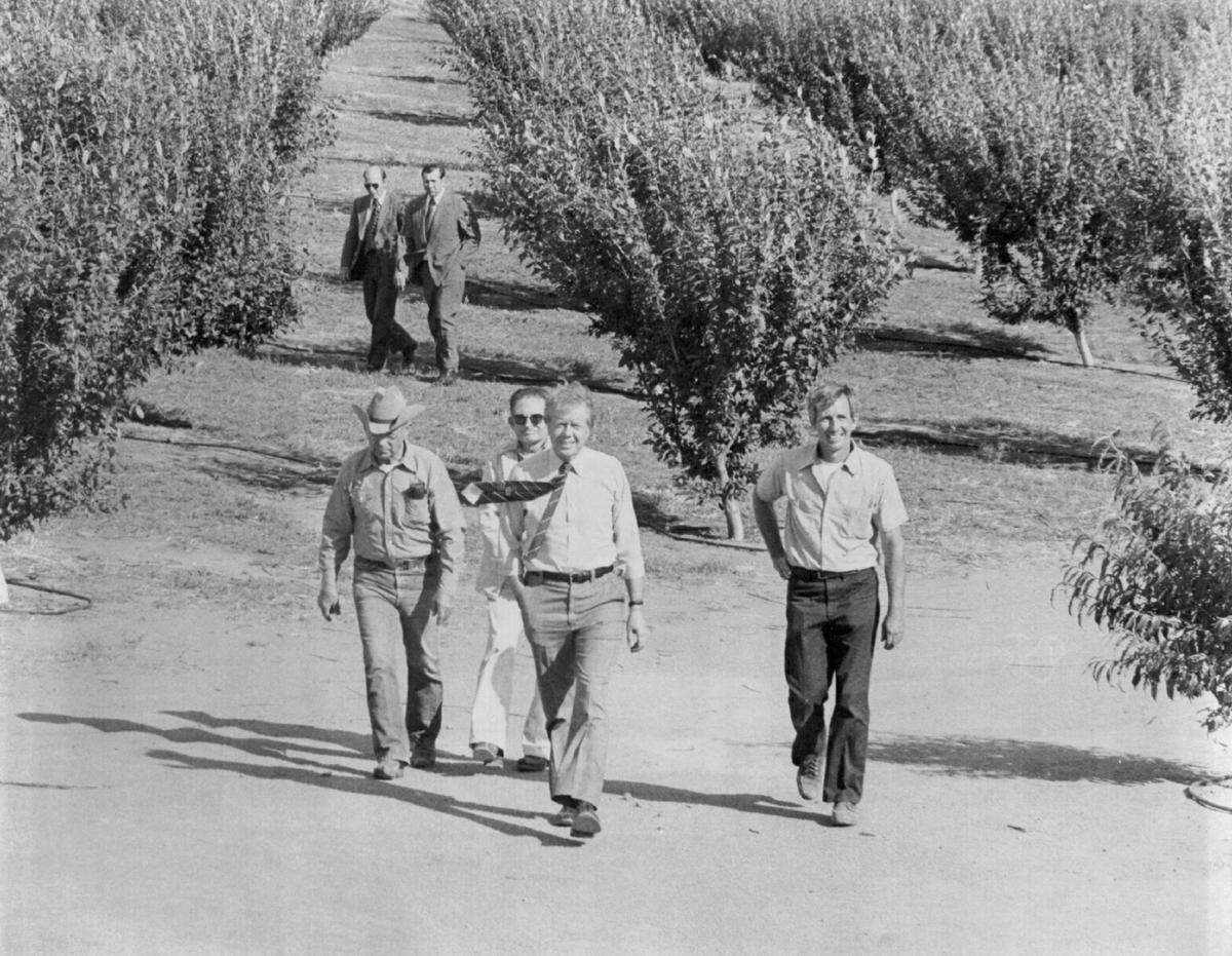 President Jimmy Carter, center, walks with rancher Manuel Silva, left, soil conservationist Red Marin, behind Carter, and Charles Kryder, right, through Kryder’s orchards near Navelencia in Fresno County on May 17, 1977. Carter was visiting the San Joaquin Valley to see the effects of the state’s drought first-hand.
