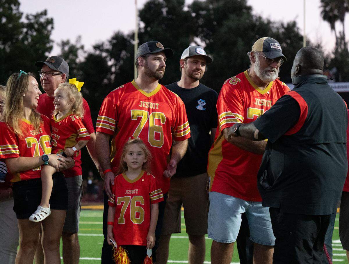Jesuit coach Marlon Blanton shakes the hand of Michael Barnes, the father of Shane Barnes, on Friday, the night Marauder Stadium was renamed in honor of the Special Operations helicopter pilot who died in a training exercise last year. His family – wife Samantha, daughters Katherine, 6, and Amelia, 2, and brother Joshua – wore his Jesuit jersey number.
