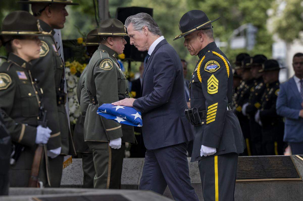 Gov. Gavin Newsom places the American flag on the monument to fallen officers during the annual California Peace Officers’ Memorial enrollment ceremony in Sacramento on Monday.