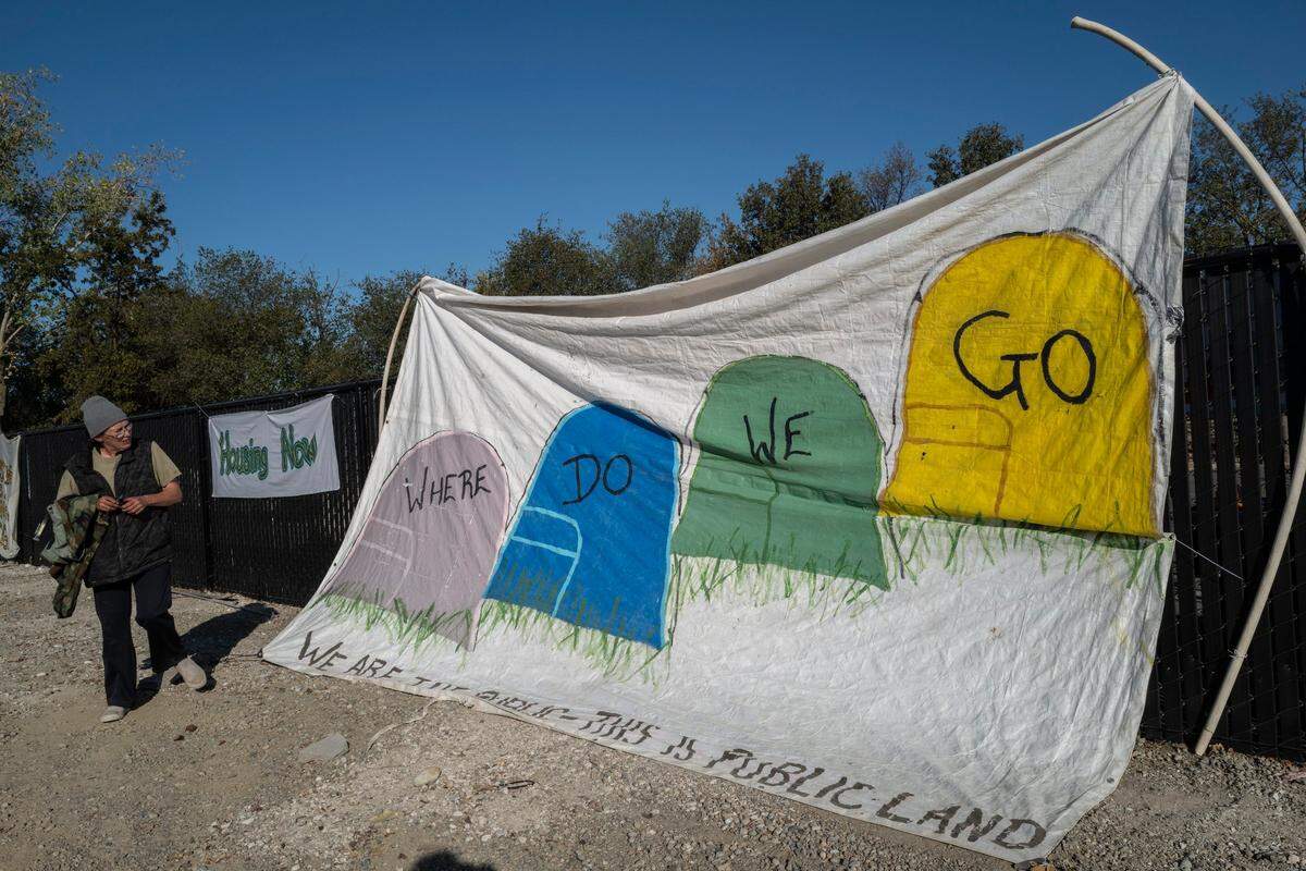 Sharon Jones, who is homeless, looks up at a banner she created Wednesday at “Camp Resolution,” a homeless encampment where she now lives on the corner of Arden Way and Colfax Street in Sacramento. “Tombstones or tents? What would you prefer?” asked Jones.