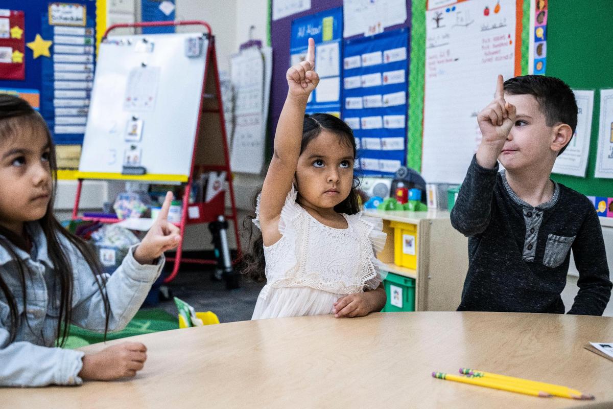 Aria Fierro, Isabella Márquez y Carter Swain, de cuatro años, dibujan la letra "f" con sus dedos en el aire.