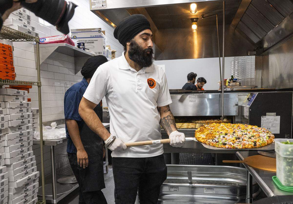 Amrit Singh, one of the franchise owners of Tandoori Pizza in Sacramento's Downtown Commons, pulls a pizza out of the oven on Wednesday. The franchise was started by UC Davis graduate Tejinder Singh and has 21 locations nationwide.  