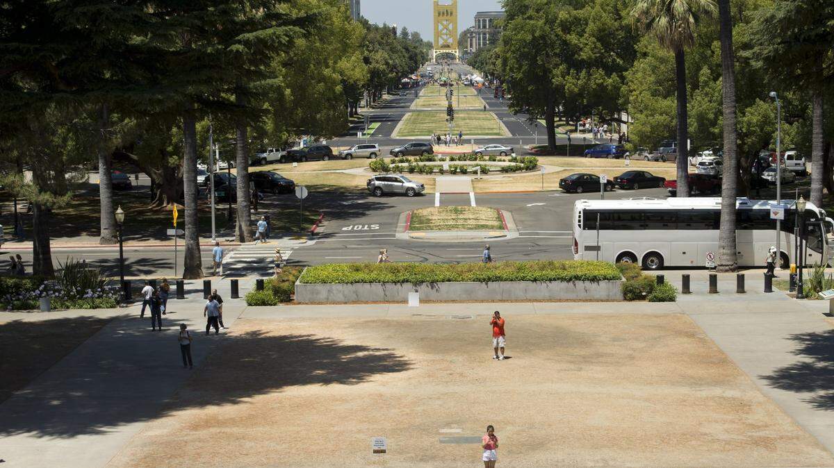 Tourists take photographs of the state Capitol in Sacramento Thursday, July 3, 2014, on the brown grass of the Capitol grounds.