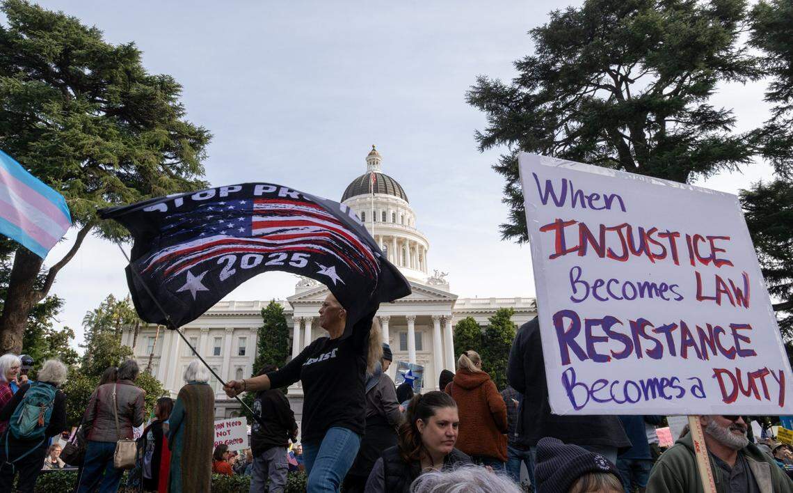 Tanya Homman waves a “Stop Project 2025” flag during a President’s Day protest organized by the members of 50501 at the state Capitol on Monday, Feb. 17, 2025, in Sacramento.