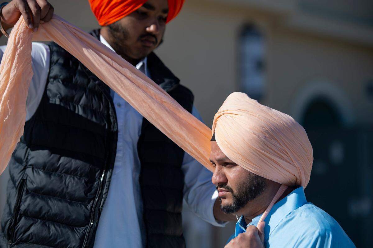Jobanpreet Sandhu ties a turban on Saba Singh before the Sacramento Sikh Society’s first Nagar Kirtan parade on Sunday, March 26, 2023, at the society’s temple in Vineyard.
