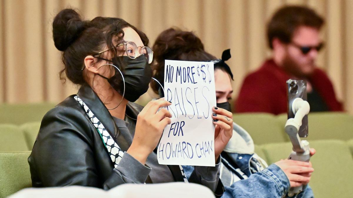 A woman holds up a sign opposing a raise for Sacramento City Manager Howard Chan at the council meeting on Tuesday, Jan. 9, 2024.