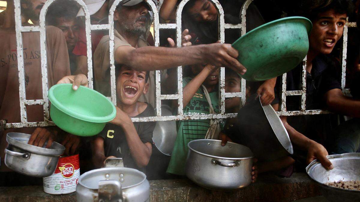 Palestinians shove to receive a hot meal at a charity kitchen in the Mawasi area of Khan Yunis in the southern Gaza Strip on July 22, 2025. 