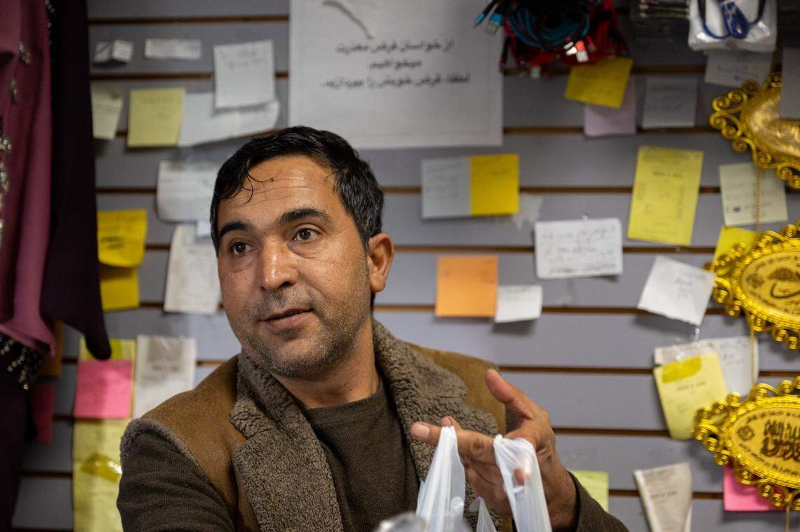 Owner Mohammad Marouf Sharifi bags groceries for a customer at Noble Halal Grocery in Yuba City last month in front of a wall of IOUs from customers unable to pay. Sharifi, who was an interpreter for the U.S. military, opened his store in 2018, a few years after moving with his family to Sacramento with special immigrant visas. He said he worries that fear of refugees will become contagious in the United States after President Trump’s executive orders.