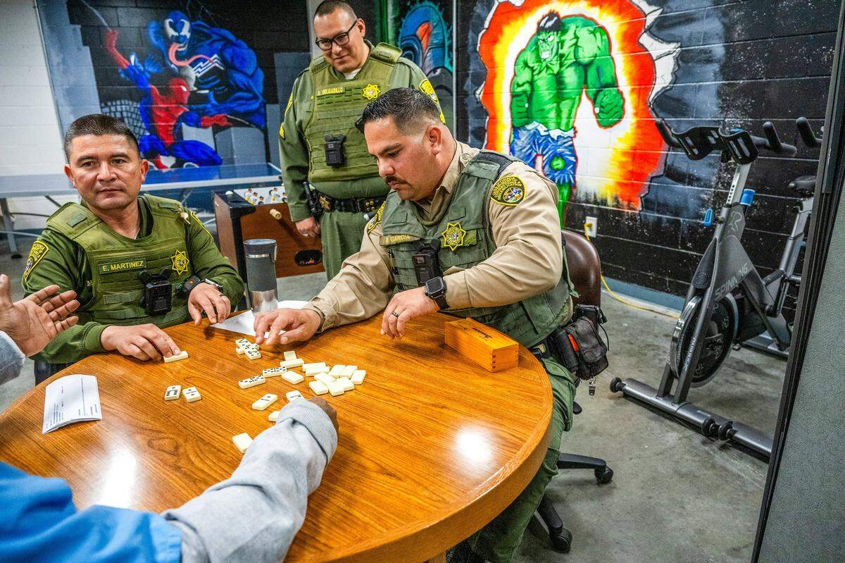 Salinas Valley State Prison correctional officers Edgar Martinez, left, and Ricardo Garcia, right, play dominoes under the watchful eye of Sgt. Danny Delgadillo with an at-risk Level 4 inmate at Salinas Valley State Prison in March. The program, part of the California Model, helps inmates and security guards have deeper connections to better understand each other and help prevent violence in the prison.