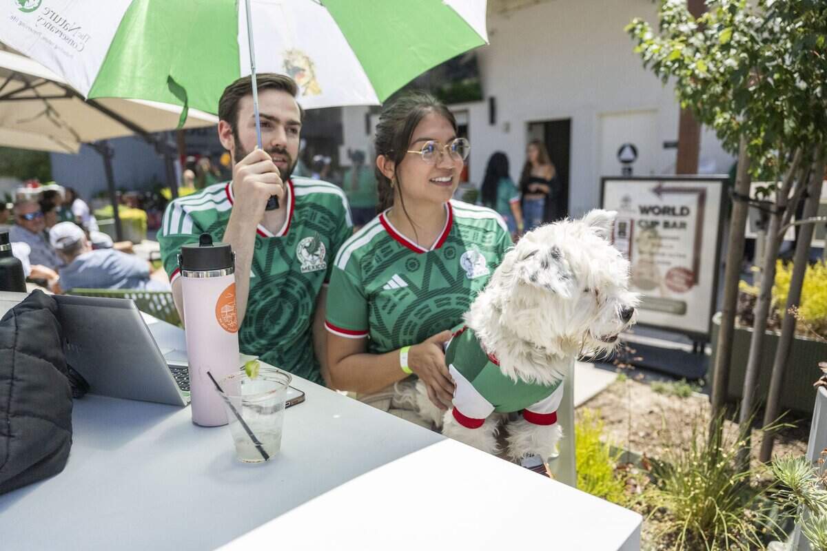 Casey Carr and his wife Anahi Garcia hold their dog Bean while they watch the World Cup with other fans during a watch party at Garden at the Line in Sacramento on Thursday. Mexico defeated South Africa 2-0 during the opening game.