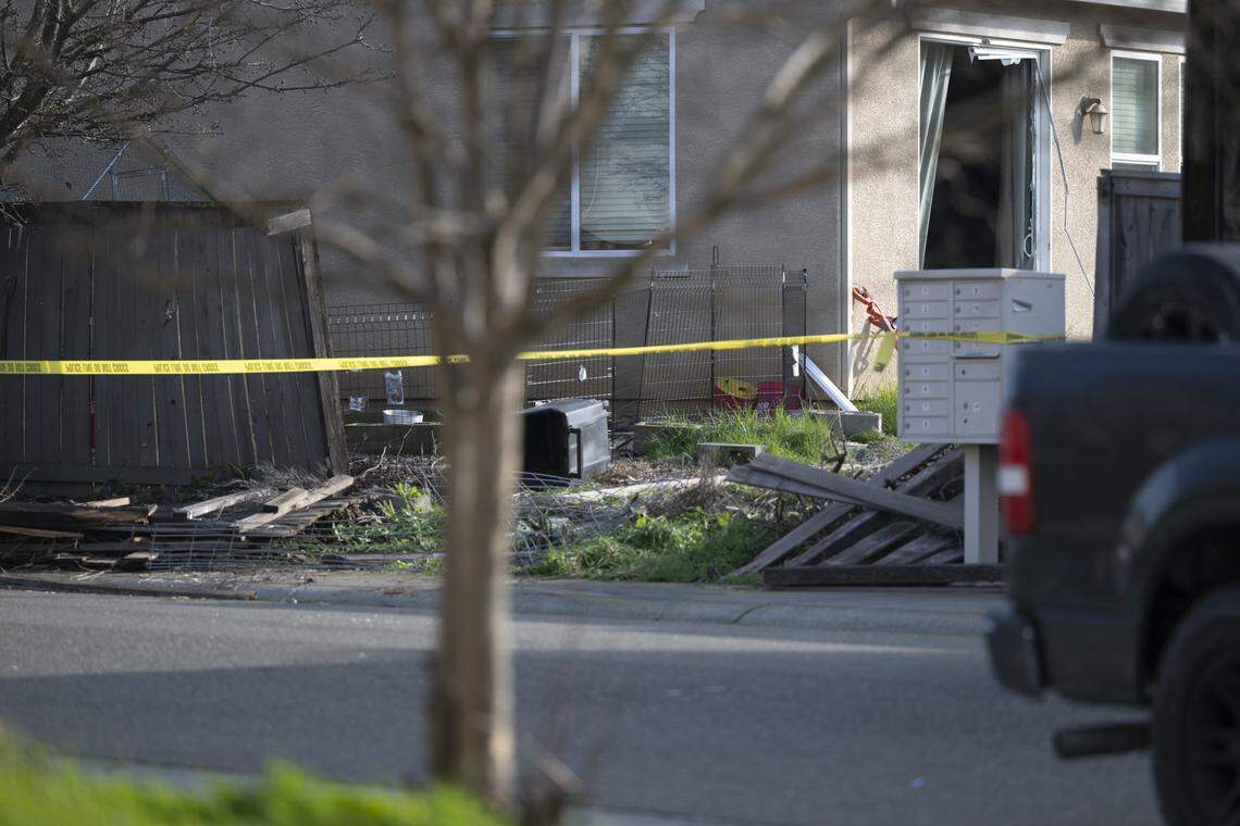 Police tape stretches in front of the flattened fence behind the home where four were found shot to death in Rancho Cordova on Tuesday, Jan. 27, 2026. The building's sliding glass door appears to be shattered.