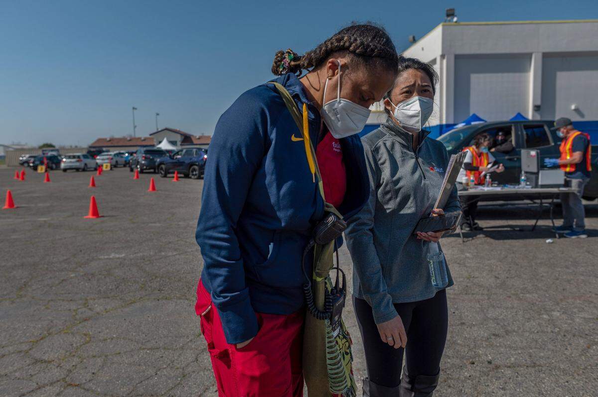 Dr. Kawanaa Carter, left, who started the Del Paso Heights vaccine clinic, is updated by clinic coordinator Nancy Bui-Thompson, right, on Thursday, March 4, 2021. The clinic has been cut off from new first-dose shots for one of Sacramento’s most underserved communities.