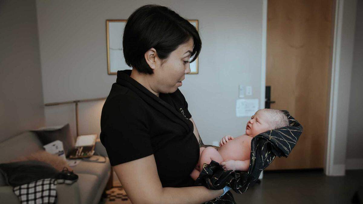 Midwife Caroline Cusenza holds Allison Rowe’s infant in the now-closed Monterey Birth & Wellness Center. The center closed because it could not afford to install galvanized steel heating vents — a state licensing requirement.