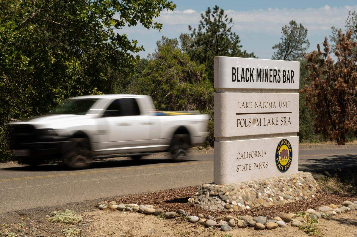 A truck drives past the updated sign for the Black Miners Bar day use area in 2022, after a state parks commission voted to temporarily rename the the facility, previously known as Negro Bar.