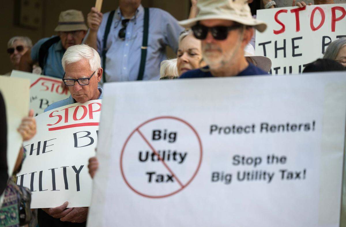Greg Sparks, left, and Rob Hawley, foreground, join a coalition of renters, seniors, affordable housing advocates and environmentalists protesting outside the California Public Utilities Commission meeting at Warren Alquist State Energy Building in Sacramento on Thursday. The CPUC approved a $24 monthly fixed charge on residential consumers who get their electricity from PG&E and other providers. 