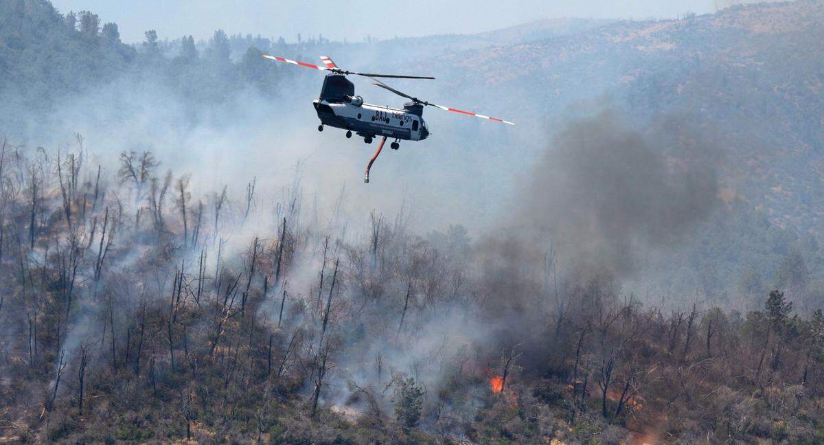 A helicopter flies over the Thompson Fire near the Oroville Dam on Wednesday, July 3, 2024.
