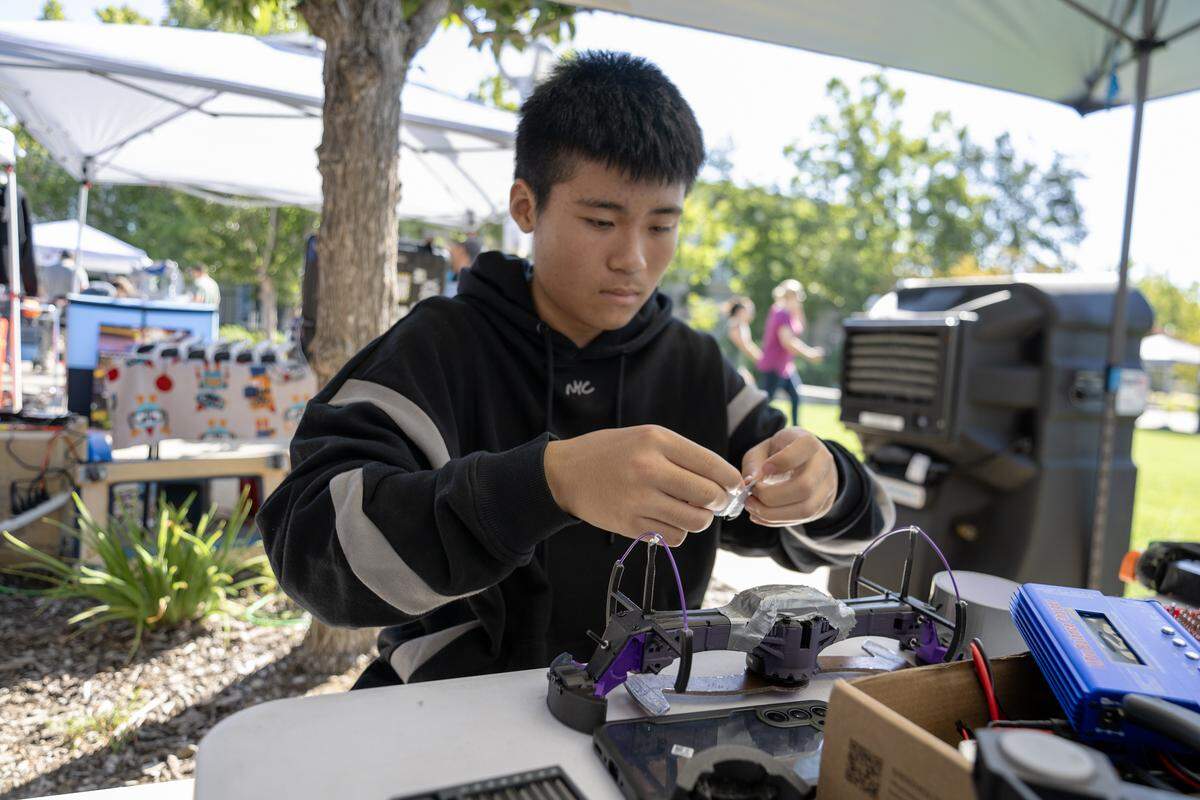 Hanson Wang, a student at Homestead High School in Cupertino, uses duct tape to stabilize his robot before his match Saturday in Roseville.