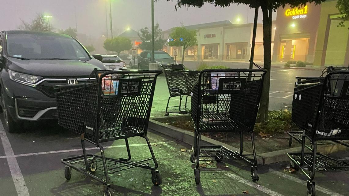 Shopping carts are left in a Safeway parking lot on a foggy morning.