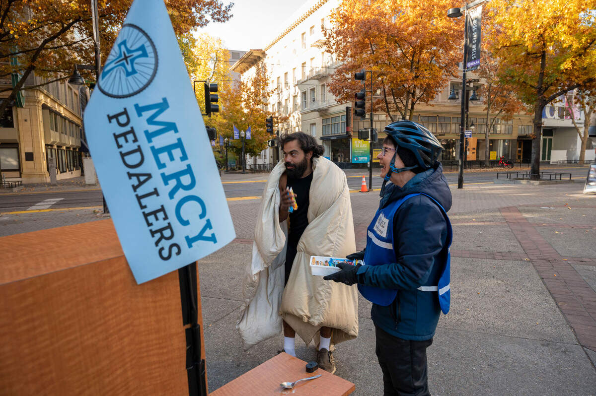 Sister Libby Fernandez with Mercy Pedalers gives out items from her adult tricycle in front of the Cathedral of the Blessed Sacrament on Nov. 10.