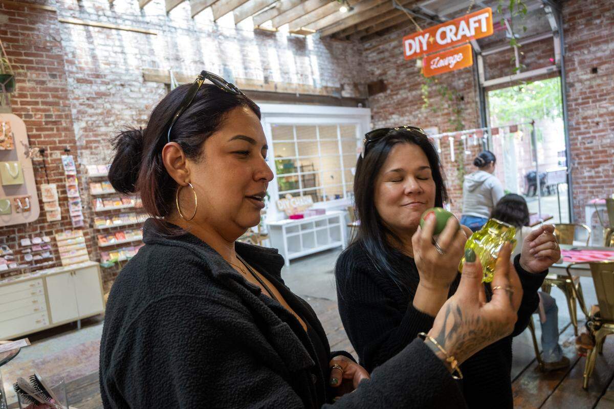 Customers Jackie Price and Tiare Lau, right, take in a candle's aroma at Golden Hour Designs in Oak Park on Tuesday, March 31, 2026.