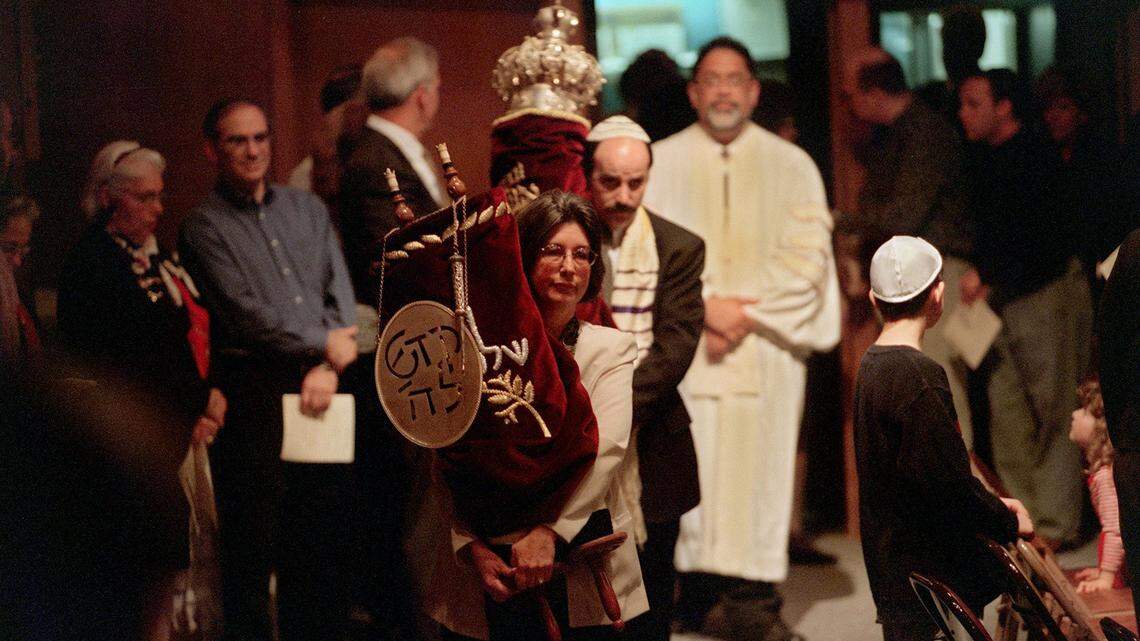 In a processional, torahs are brought into the sanctuary by congregational leaders at Congregation B’Nai Israel to be placed in the ark on Saturday, March 11, 2000. The Saturday service marked the first time the sanctuary has been used since the synagogue was firebombed in June 1999. There is a plan to find a permanent replacement for the sanctuary.