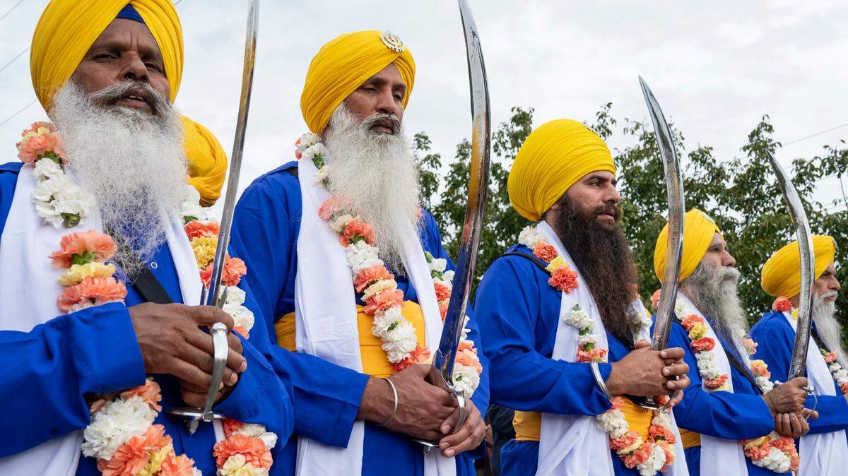 The five men, known as the Panj Pyare, stand in front of the float with the Holy Scripture at the Yuba City Nagar Kirtan Sikh parade on Nov. 5, 2023.