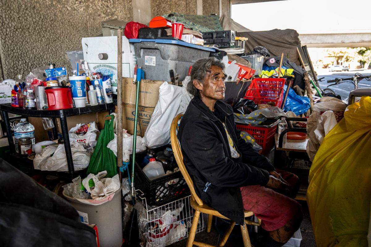 Ricky Scott Luna, 56, sits at his camp on the Broadway sidewalk under Highway 99 on Wednesday as homeless residents in the area are informed about a new city ordinance that requires four feet of clearance so that wheelchairs users can pass on the sidewalk.