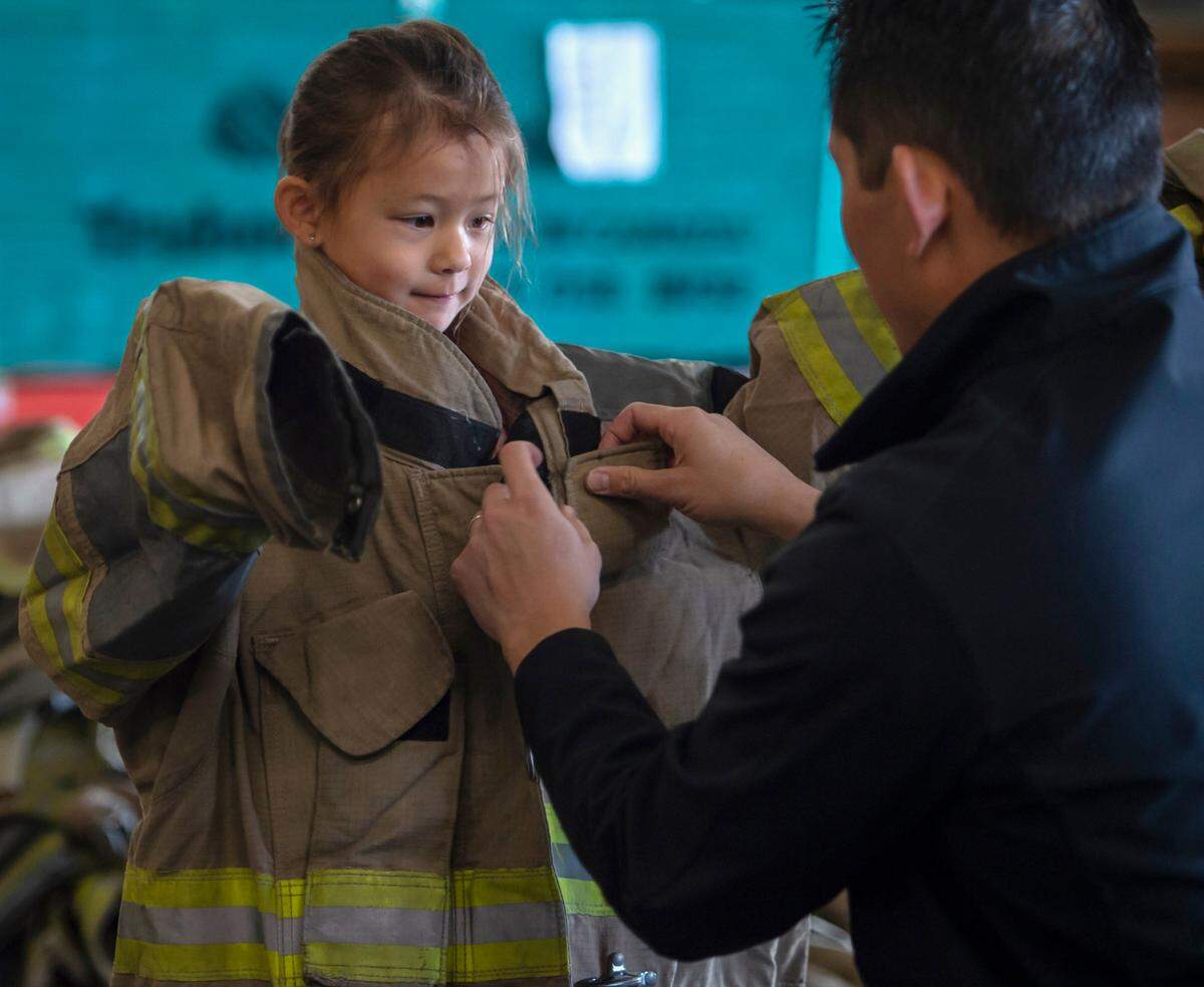 Sacramento Fire Department Capt. Lawrence Whang fits a jacket on his 5-year-old daughter Layla at the Sacramento Area Girls Fire Camp at McClellan Park in October. Whang wanted to give her to a chance to see a lot of women doing this job, he said.