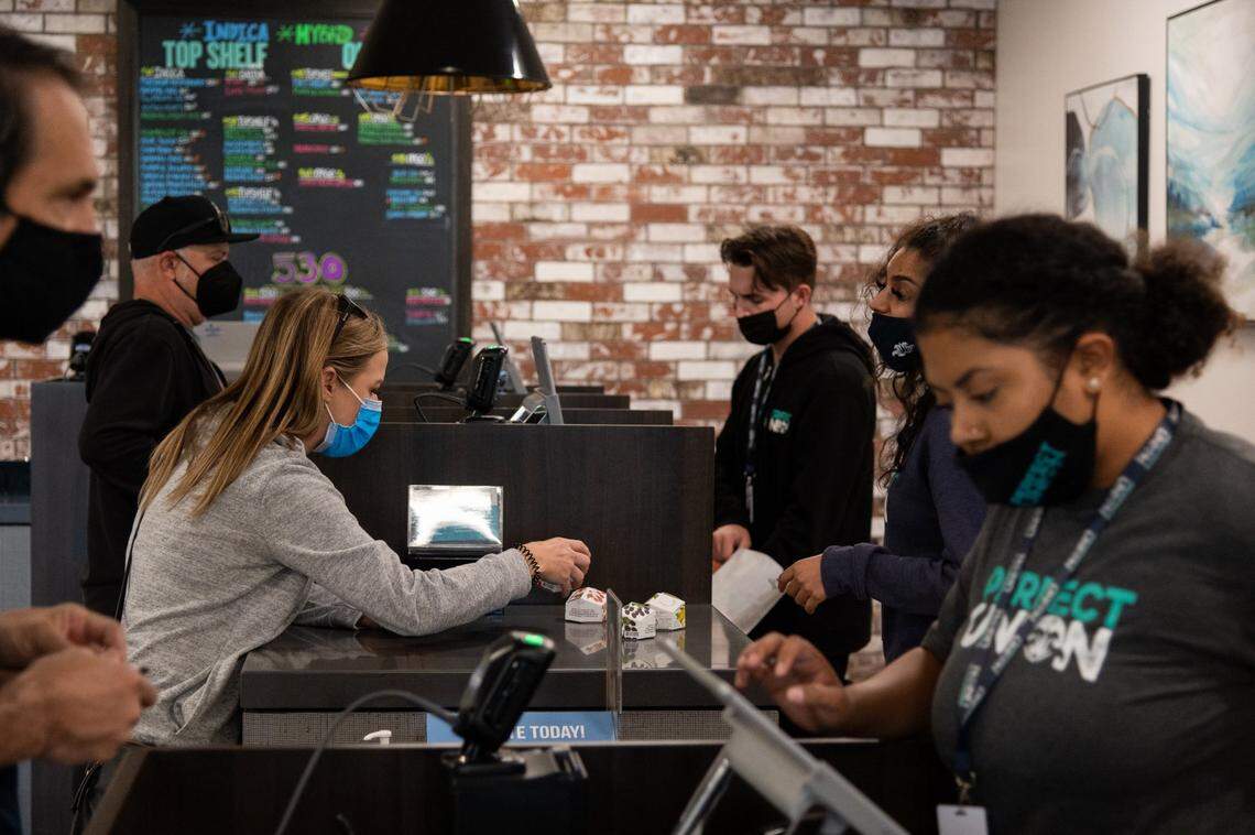 Budtenders complete sales transactions with clients at the Perfect Union marijuana dispensary on Friday, Oct. 22, 2021, in Sacramento.