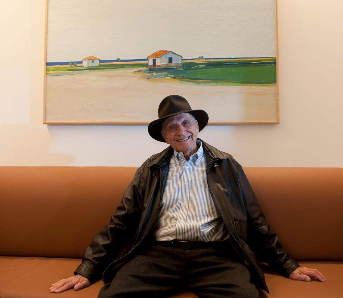 Gregory Kondos is photographed with one of his paintings in 2013 at the Crocker Art Museum at his show titled “A Touch of Blue.”